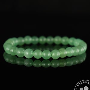 May include: A green gemstone bracelet made of round beads. The bracelet is on a black background.