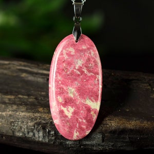 Peut inclure: Un pendentif ovale de couleur rose et blanche avec un motif marbré, suspendu à une chaîne en argent.
