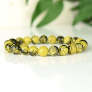 May include: A yellow and black gemstone bracelet with round beads.