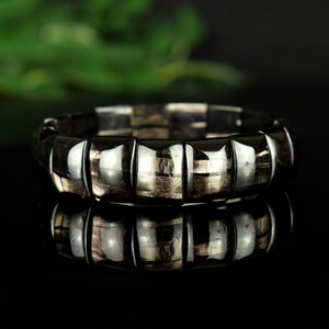 May include: A black and silver bracelet made of multiple round beads. The beads have a shiny, metallic finish.