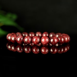 Peut inclure: Un bracelet en pierres précieuses rouges avec des perles rondes. Le bracelet est fait de pierres naturelles et a une finition polie.