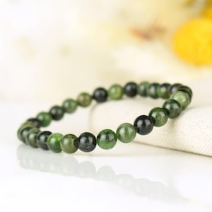 May include: A green gemstone bracelet with round beads. The bracelet is made of natural stones and has a simple design.