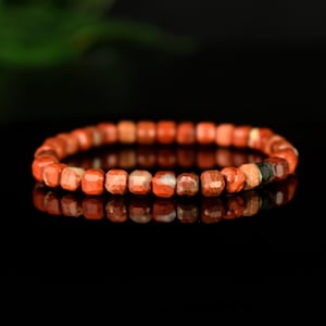 Op de afbeelding: Rode jaspis armband met gefacetteerde kralen. De armband is gemaakt van natuurlijke stenen en heeft een eenvoudig ontwerp.