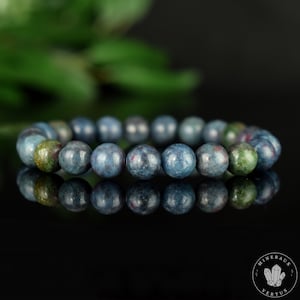 Könnte beinhalten: Ein blaues Edelstein-Armband mit runden Perlen. Die Perlen haben eine marmorierte Optik mit grünlichen und rosafarbenen Nuancen.