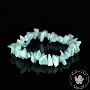 Peut inclure: Un bracelet en pierres naturelles composé de petites pierres bleues. Le bracelet est composé de nombreuses petites pierres irrégulières. Le bracelet est sur un fond noir.