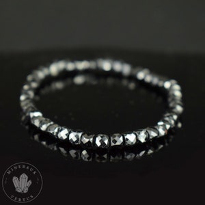 May include: A black hematite beaded bracelet with faceted beads. The bracelet is made of natural hematite stones and is designed to be worn on the wrist.