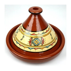 Puede incluir: Una tagine de terracota con una tapa cónica que presenta un patrón geométrico en tonos de amarillo, azul, rojo y naranja. La tagine es una olla de cocción tradicional marroquí.