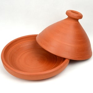 Peut inclure: Une tagine en terre cuite avec un couvercle. La marmite est ronde et a une base large et peu profonde. Le couvercle est en forme de dôme et a un petit bouton sur le dessus.