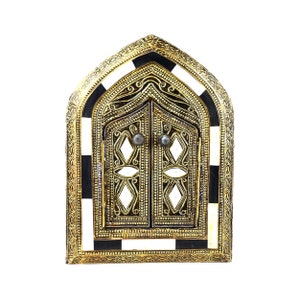 Puede incluir: Un espejo de metal dorado con un borde a cuadros en blanco y negro. El espejo tiene forma de arco de entrada con detalles intrincados.