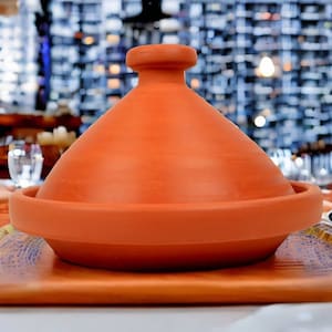 Könnte beinhalten: Eine Terrakotta-Tagine mit einem gewölbten Deckel. Die Tagine ist ein traditioneller marokkanischer Kochtopf, der zum langsamen Garen verwendet wird.