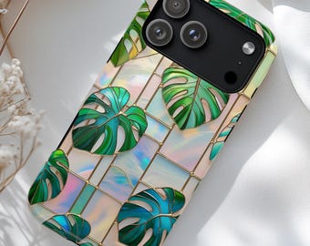 May include: A phone case featuring a tropical monstera leaf design. The case has a mosaic-like pattern with green leaves and iridescent squares, outlined in gold. The phone's camera lenses are visible at the top.