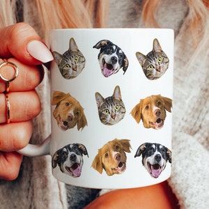 May include: White ceramic mug with a repeating pattern of dog and cat faces. The mug is being held by a person's hand.