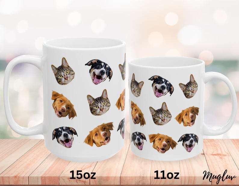 May include: Two white ceramic mugs with different sizes, 11oz and 15oz, featuring a pattern of various animal faces, including cats and dogs. The mugs are on a wooden surface.