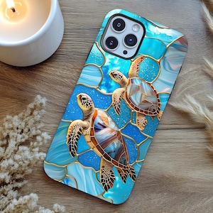 May include: A blue phone case featuring a stained-glass design with two sea turtles. The turtles have brown, tan, and blue shells, with gold-colored outlines. The background has a blue and white water pattern.