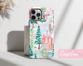 May include: A white phone case with a winter village design. The design features pink houses, green trees, and a blue sky. The case has a cutout for the phone's camera.