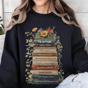 May include: Black sweatshirt with a stack of books printed on the front. The books are arranged vertically and include titles like "Pride and Prejudice", "Moby-Dick", "Jane Eyre", "The Great Gatsby", "Wuthering Heights", "To Kill a Mockingbird", "The Catcher in the Rye", "Frankenstein", "The Scarlet Letter", and "The Adventures of Huckleberry Finn".