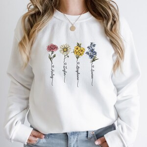 Pu&ograve; includere: Felpa bianca con un design floreale e quattro nomi: Hailey, Taylor, Stephanie e Lauren.
