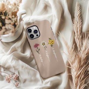 May include: A light brown phone case with a floral design and three names: "Lola", "Taylor", and "Stephanie".