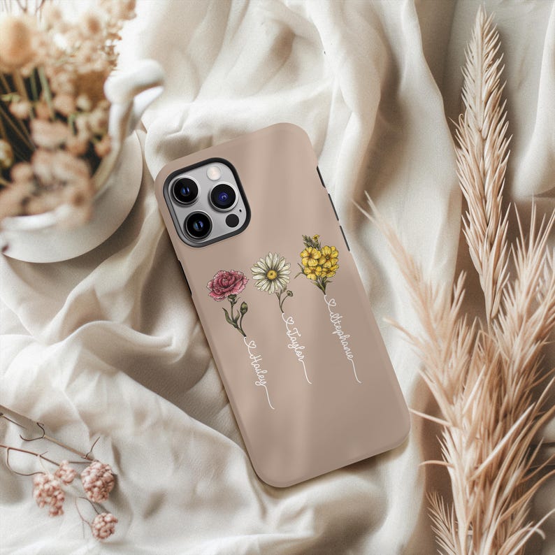 May include: A light brown phone case with a floral design and three names: "Lola", "Taylor", and "Stephanie".