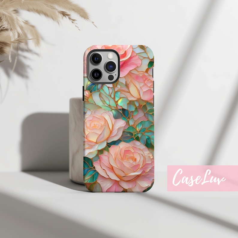 May include: A phone case with a floral design featuring pink roses and green leaves. The case has a stained glass effect with iridescent colors.