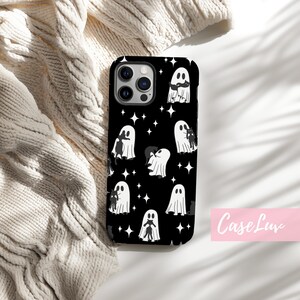 May include: Black phone case with a repeating pattern of white ghosts and stars on a black background. The phone case has a camera cutout and the text "Case Luv" in pink.