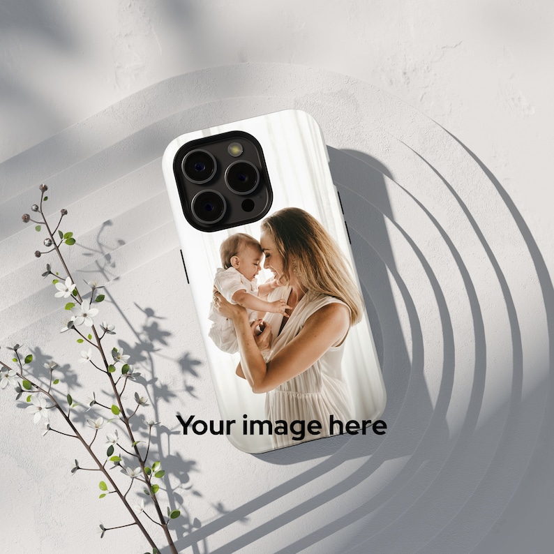Peut inclure: Coque de smartphone noire avec une photo d'une m&egrave;re et d'un enfant. L'&eacute;tui a une finition brillante et le texte "Your image here" est imprim&eacute; en bas. L'&eacute;tui est pos&eacute; sur une surface blanche.