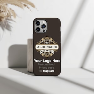 Peut inclure: Coque de t&eacute;l&eacute;phone marron avec le texte "ALDENAIRE BARBECUE SINCE 2022" dans un embl&egrave;me d&eacute;coratif. La coque pr&eacute;sente &eacute;galement le texte "Your Logo Here" et "Personalized Phone case for MagSafe".