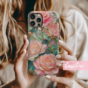 May include: A phone case with a floral design featuring pink and white roses with gold accents. The case has a stained glass effect and is made of a durable material.