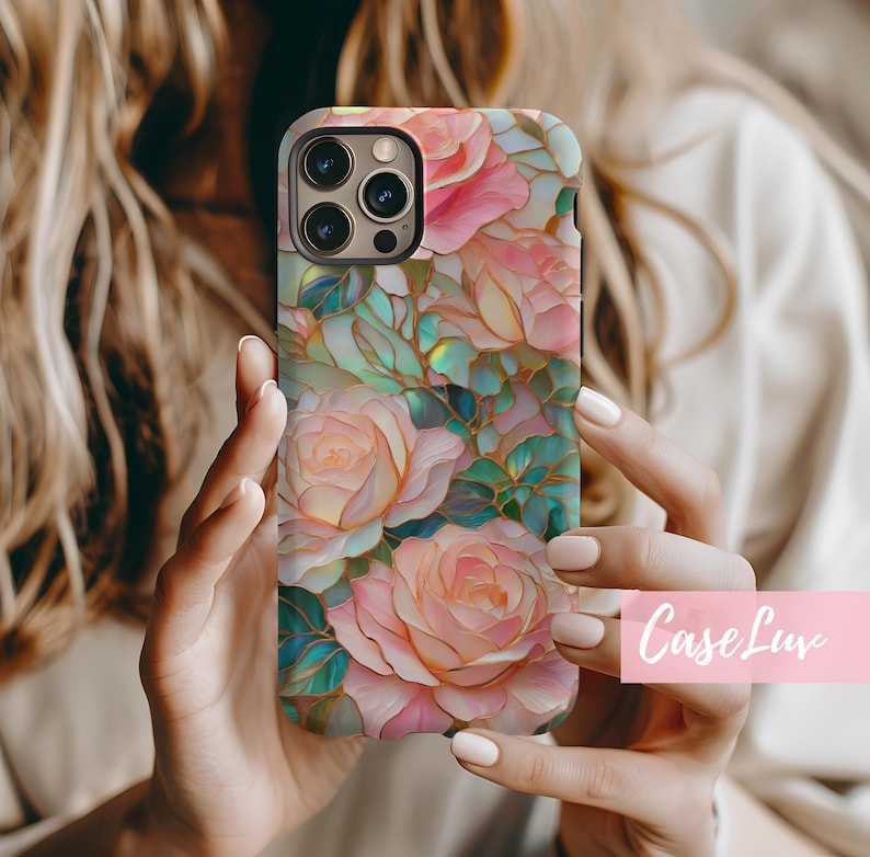 May include: A phone case with a floral design featuring pink and white roses with gold accents. The case has a stained glass effect and is made of a durable material.