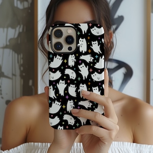 May include: A black phone case with a white ghost and cat pattern. The case has a colorful star pattern and is designed for an iPhone.
