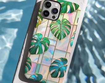 May include: A phone case featuring a stained-glass design with green monstera leaves. The case has a grid pattern with gold-colored lines and iridescent glass-like squares. The leaves have varying shades of green and blue.