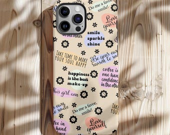 May include: A beige phone case with a variety of colorful text and floral graphics. The case features phrases like "Love yourself," "Smile," and "Be your own reason to smile." The case is decorated with small black flower icons.