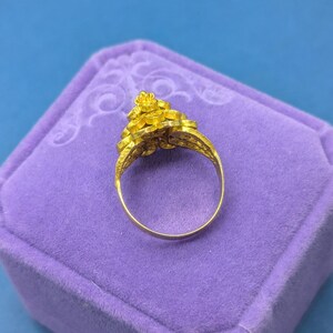 May include: A gold ring with a floral design. The ring is in a purple velvet ring box.