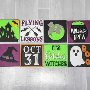 Puede incluir: Ocho letreros de madera con temas de Halloween. Los letreros están pintados en varios colores, incluyendo verde, negro, morado y naranja. Los letreros presentan imágenes y texto, como una casa encantada, un sombrero de bruja, un caldero, un fantasma y las palabras "Flying Lessons", "Witches Brew", "Oct 31", "It's October Witches", y "Boo".