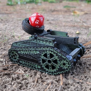 May include: A black and green toy tank with a red 19-sided die on top of the turret. The tank has a detailed design with gears and tracks.