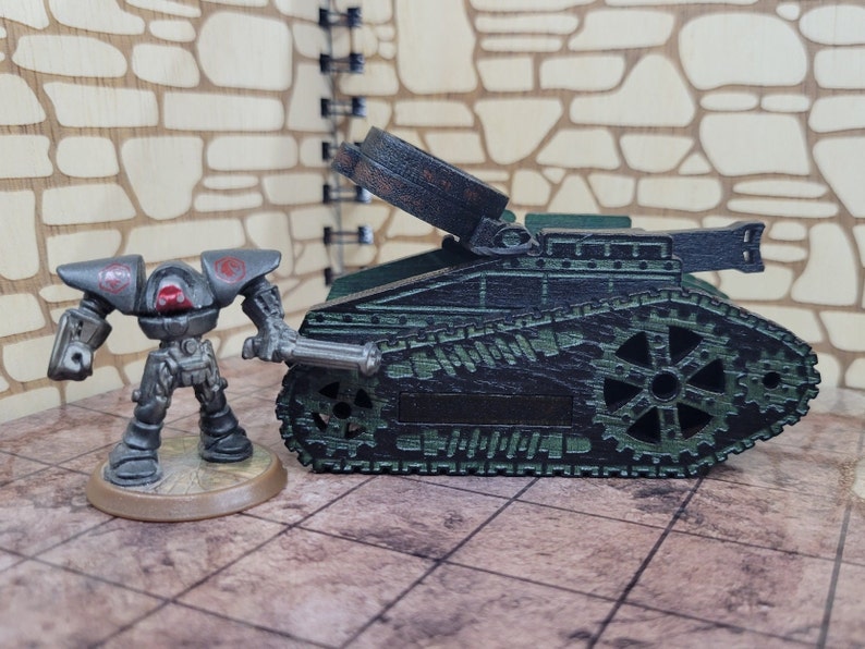 May include: A dark green toy tank with a black and silver cannon. The tank has a detailed design with gears and tracks. A small, gray robot stands next to the tank.