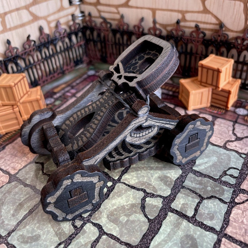 May include: A wooden skeletal catapult with a skull design. The catapult is painted brown and black and has a bone-like design. The catapult is on a stone floor.