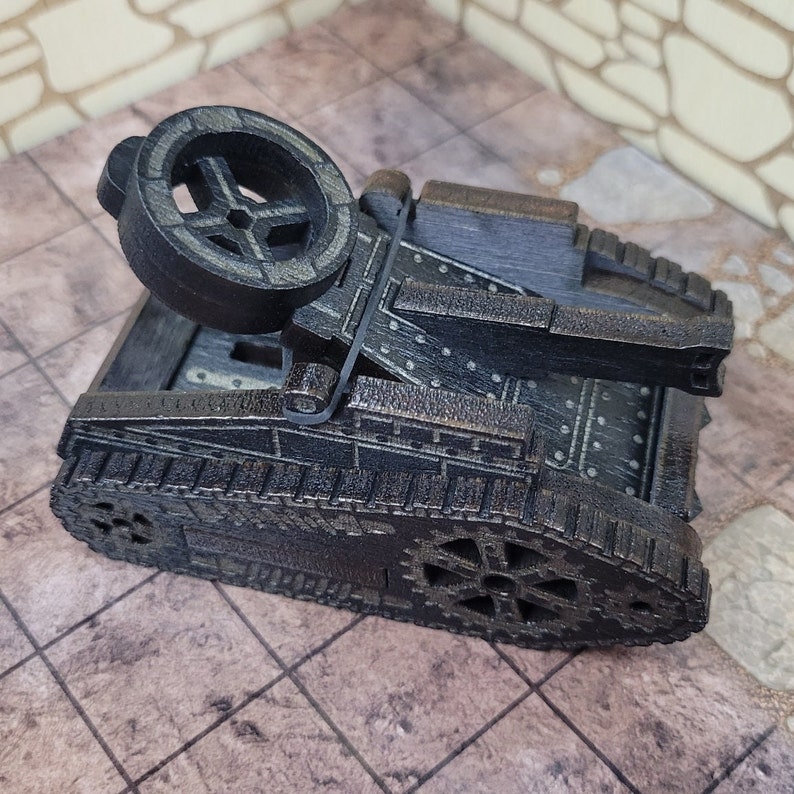 May include: A black metal model of a tank with a large wheel on the front. The tank has a detailed design with rivets and gears.