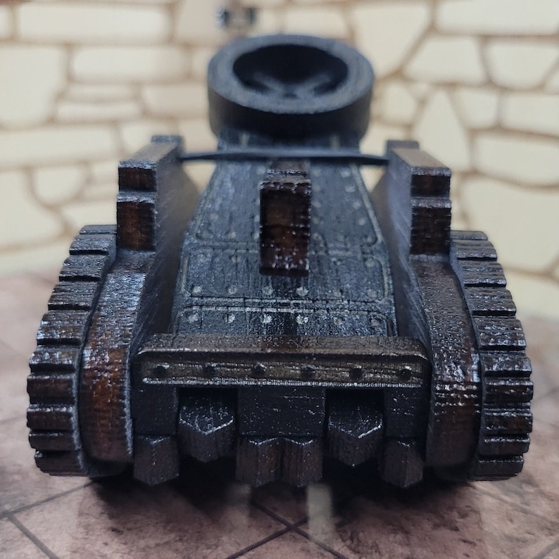 May include: A wooden model of a medieval siege weapon, a catapult, with a dark brown finish and a detailed design. The catapult has a large wheel on each side and a raised platform in the back.