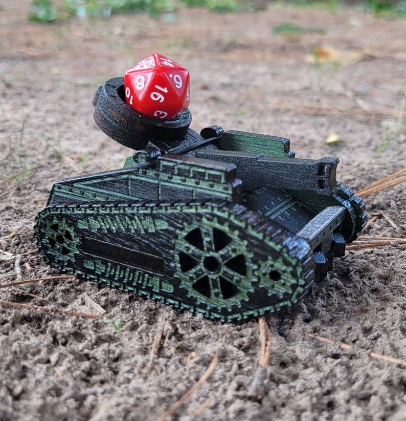 May include: A black and green toy tank with a red 19-sided die on top of the turret. The tank has a detailed design with gears and tracks.