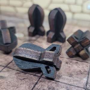May include: Five wooden game pieces in various shapes, including a bomb, a cross, and a cone. The pieces are painted black with brown accents.