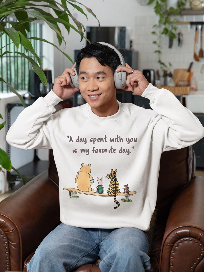 May include: A white sweatshirt with a Winnie the Pooh and friends graphic. The text on the sweatshirt reads "A day spent with you is my favorite day."