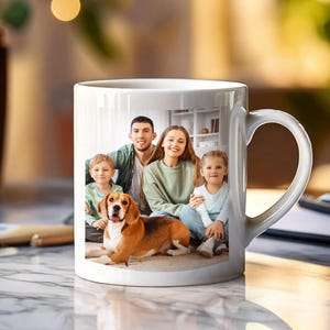 May include: White ceramic mug with a photo printed on it. The photo shows a family of four with a dog. The family is smiling and the dog is sitting in front of them.