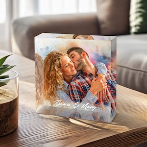May include: A personalized acrylic block with a watercolor-style photo of a couple embracing. The text "James & Mary" is written in white script at the bottom of the block.