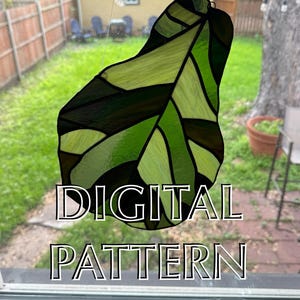 May include: A stained glass leaf design in shades of green and brown, hanging in front of a window. The leaf is divided into geometric sections. The words "DIGITAL PATTERN" are overlaid on the image.