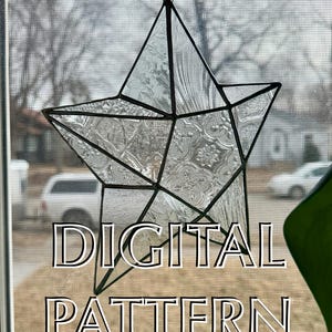 May include: A clear, star-shaped stained glass suncatcher with black metal framing. The glass has textured and patterned sections. The words "DIGITAL PATTERN" are printed in white with a black outline.