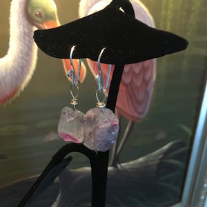 May include: A pair of silver earrings with green and pink fluorite stones hanging from the earrings.