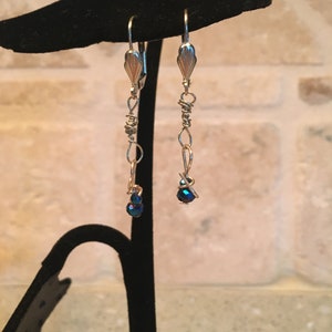 May include: A pair of silver dangle earrings with blue iridescent glass beads and wire accents.