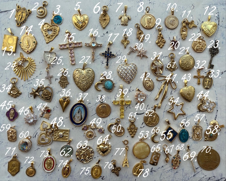 Puede incluir: Una colecci&oacute;n de 78 dijes dorados con varios dise&ntilde;os religiosos y simb&oacute;licos. Los dijes est&aacute;n dispuestos en filas sobre una superficie blanca. Algunos de los dijes presentan corazones, cruces, estrellas y otros s&iacute;mbolos religiosos.