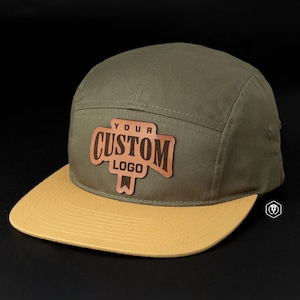 May include: A green and tan baseball cap with a brown leather patch that says "YOUR CUSTOM LOGO".